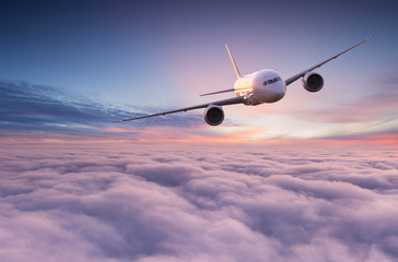 Commercial airplane jetliner flying above dramatic clouds in beautiful light. Travel concept.