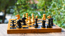 Vintage Wooden Chess Board And Figures On Table In Garden