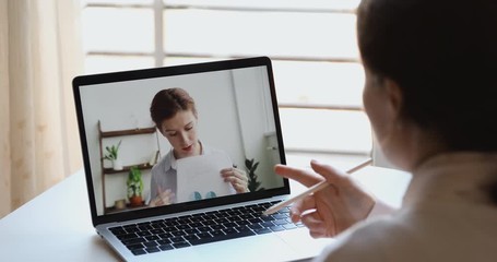 Videoconference meeting concept. Female manager discussing financial report with distance partner making webcam presentation elearning training conference video call. Over shoulder laptop screen view