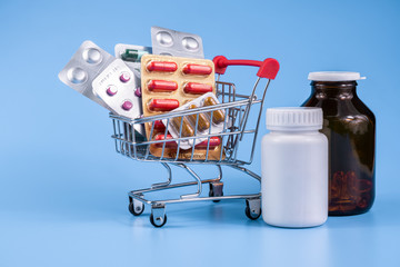 Wall Mural - Medicine, vitamins and antioxidant supplements in trolley or shopping cart on blue background