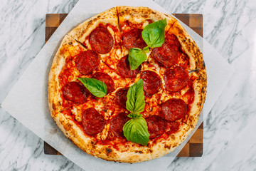 Italian pizza with mozzarella cheese and basil on a marble table