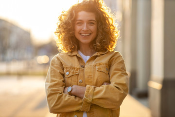Wall Mural - Portrait of young woman with curly hair in the city
