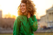 Leinwanddruck Bild - Portrait of young woman with curly hair in the city
