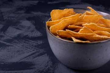 Nachos in a ceramic bowl on the grey table. Corn tortilla chips. Mexican cuisine snack