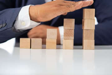 Businessman Wooden cubes on a desk in the office, Concept: Business to succeed that challenges teamwork, design development strategy investment, symbol Financial advisor shows  to asset growth