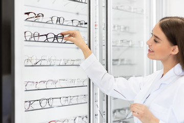 Fototapete - Female optometrist helping client to choose glasses