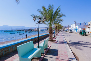 Tadjoura, Djibouti - November 09, 2019: Palms and Boats on the Sea Coastline under Blue sky