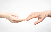 A Young Hand Reaches For An Old Hand. Help For The Elderly Concept.