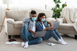 © Prostock-studio - Self-isolated couple working remotely on laptops at home, wearing medical masks