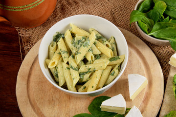 pasta in a creamy spinach sauce with fresh spinach leaves and blue cheese on a wooden kitchen board