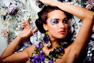 floral face art with anemone in jewelry, sensual young brunette woman in studio close up