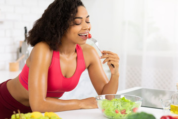 Wall Mural - Beautiful young african girl eating vegetable salad