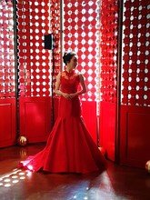 Model Wearing Red Evening Gown While Standing Against Wall