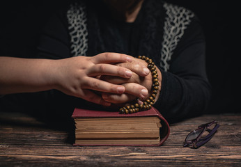 Girl and Old Woman with closed hands holding rosary on holy book staying at home and praying for protection ageainst coronavirus covid-19 pandemi concept.