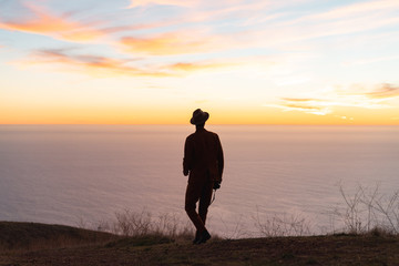 Wall Mural - silhouette of man standing on hill during sunrise