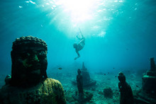 Scuba Diver Swimming Underwater Near Buddha Statues