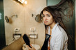 © eldarnurkovic - Woman doing her hair styling with a brush at home.Bad hair day.Daily hairstyle preparation routine.Heat damage,split ends,dry hair loss.Getting ready for work.Blow drying DIY haircut.Home hair care