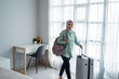 © Odua Images - beauty young hijab traveler walk and carrying her bag and holding suitcase in the front windows with curtain
