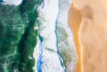 Top Down Aerial View Of Waves Crashing Into The Beach With Beautiful Green Water And Soft Sand