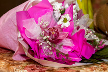 A Large Bouquet Of Pink Orchids And White Chrysanthemums Decorated In Bright Pink Paper Lies On The Table