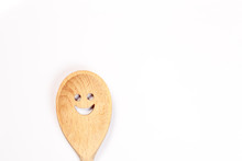 Close-up Of Wooden Spoon With Anthropomorphic Smiley Face Over White Background