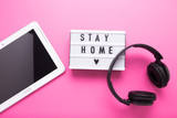 Fototapeta Do pokoju - Stay home, boxing inscription. Remote online work at home. Headphones tablet and diary on a pink background.