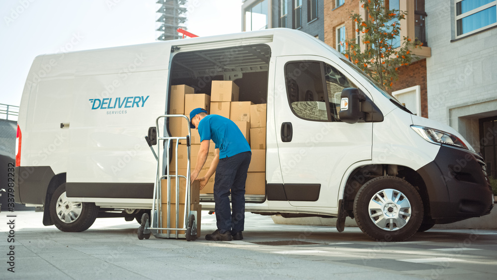 Obraz Courier Takes out Cardboard Box Package From Opened Delivery Van Side Door. Professional Courier / Loader helping you Move, Delivering Your Purchased Items Efficiently fototapeta, plakat