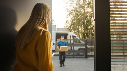 Delivery Man House and Delivers Cardboard Box Package to a Beautiful Young Woman. In the Background Cute Suburban Neighbourhood.