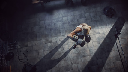 Wall Mural - Professional Female Boxer Exercises Air Punches while Wearing Sportswear and Fighting Gloves in the Hardcore Gym. Strong Beautiful Girl Kickboxing and Self Defense Workout. Top Dramatic View