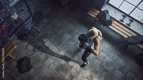 Fotografía Professional Female Boxer Exercises Air Punches while Wearing Sportswear and Fighting Gloves in the Hardcore Gym