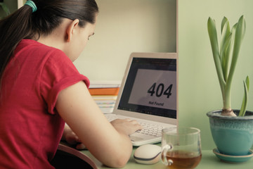 Teen girl sitting at a table with a laptop.