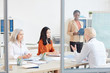 © Seventyfour - Diverse group of successful businesswomen planning project during meeting in conference room, shot from behind glass wall, copy space