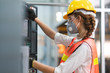 © Supachai - Female Engineer wear face mask with safety vest and yellow helmet operating control CNC Machinery at factory Industrial