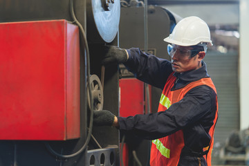 Asian engineer working inspection machine equiptment in line production at a factory industrial