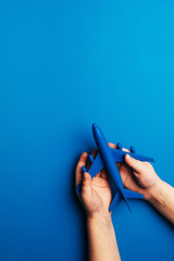 Hands carefully hold the plane model. Plane on a blue colored background. Security and travel concept