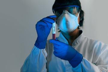 Doctor scientist in protective gloves, mask and glasses holding test tube with blood for 2019-nCoV analyzing.Blood Sample. Corona virus outbreaking. Epidemic virus Respiratory Syndrome.