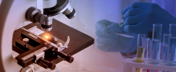 Wall Mural - close-up shot of microscope with a blurred picture of research in laboratory