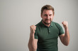 © Cipri Suciu  - Portrait of serious stylish attractive man with thick beard, dressed in casual green t shirt making winner gesture happy face