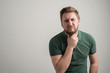 © Cipri Suciu  - Portrait of serious stylish attractive man with thick beard, dressed in casual green t shirt gesturing neck ache
