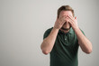 © Cipri Suciu  - Portrait of serious stylish attractive man with thick beard, dressed in casual green t shirt covering eyes like blind gesture
