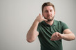 © Cipri Suciu  - Portrait of serious stylish attractive man with thick beard, dressed in casual green t shirt showing calling or contact gesture