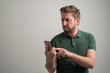 © Cipri Suciu  - Portrait of serious stylish attractive man with thick beard, dressed in casual green t shirt using mobile applications texting on cellphone