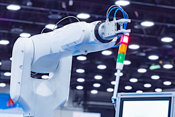 Wall Mural - The robot arm is white. Hand of an industrial robot in the background of the production of lighting fixtures. Development of programs to control industrial robots. Production programming. CNC machine