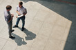 © DragonImages - Young businessman with opened planner standing outdoors and talking to colleague about work, view from above