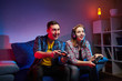 © bondvit - Portrait of crazy playful couple, Gamers enjoying Playing Video Games indoors sitting on the sofa, holding Console Gamepad in hands. Resting At Home, have a great Weekend