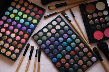 A palette of shadows and brushes on the table next to the flowers