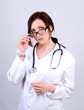 © dimas830 - Portrait of a young doctor woman in a white coat and mask with a stethoscope on a gray background