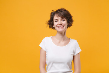 Wall Mural - Smiling beautiful young brunette woman girl in white t-shirt posing isolated on yellow orange background studio portrait. People sincere emotions lifestyle concept. Mock up copy space. Looking camera.