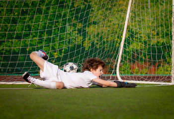 Wall Mural - junior soccer goalkeeper. Disappointed boy in white goalie sportswear. Goalkeeper missed a goal during friendly match.