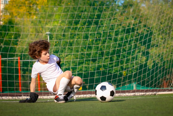 Wall Mural - Summer soccer tournament for young kids. football club. emotions and joy of the game. Young goalie. Kids - soccer champion. Boy goalkeeper in football sportswear on stadium with ball. Sport concept.